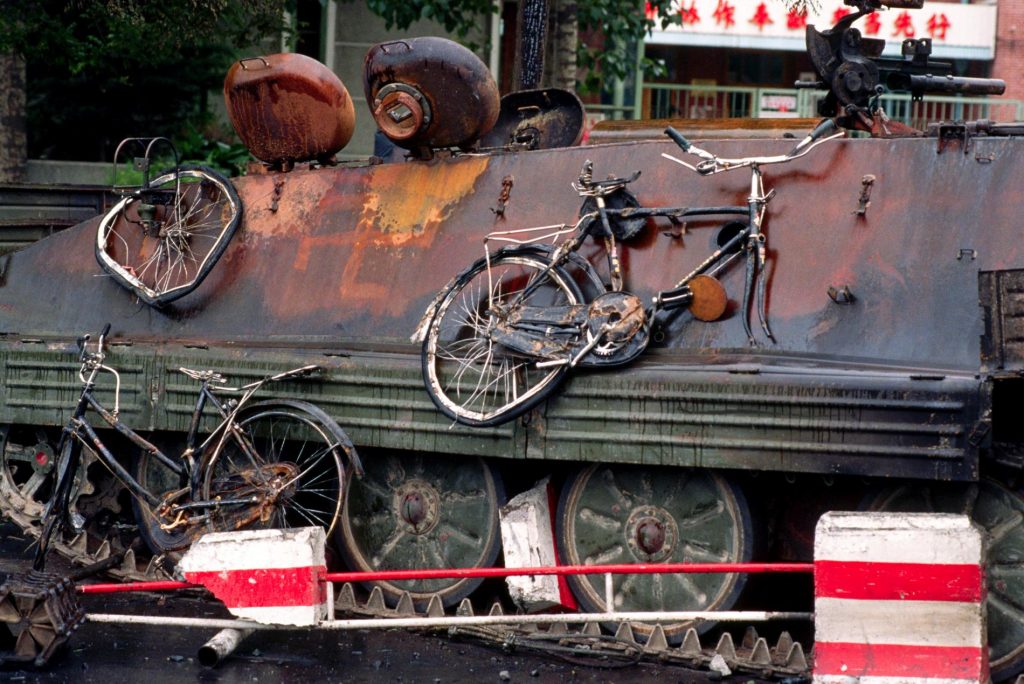 解放軍坦克欲進入天安門廣場時，被學生放火試圖阻止攻勢；扭曲變形的腳踏車掛在上頭。 